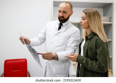 Male Doctor Explaining Xray Report To Young Female Patient