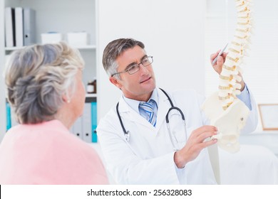 Male doctor explaning anatomical spine to senior woman in clinic - Powered by Shutterstock