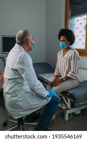 Male Doctor With Face Mask Examining His Female Patient In Clinic Office