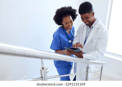 Male Doctor And Female Nurse With Digital Tablet Discussing Patient Notes On Stairs In Hospital - Powered by Shutterstock