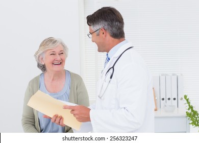 Male Doctor And Female Patient Conversing Over Reports In Clinic