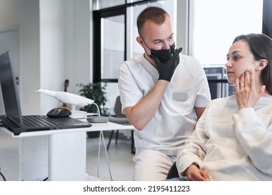 Male Doctor And Female Patient Discussing Treatment In Front Of Laptop Screen At Dentist Office