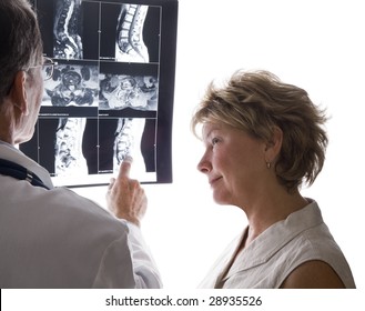 Male doctor and female patient discussing film scans of the patient's back. - Powered by Shutterstock