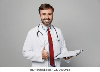 Male doctor fun happy man wears white medical gown suit work in hospital hold clipboard with paper documents show thumb up gesture isolated on plain grey color background. Healthcare medicine concept - Shutterstock ID 2270410915