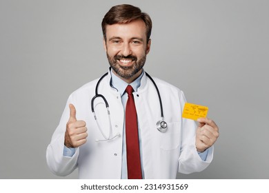 Male doctor fun man wears white medical gown suit stethoscope work in hospital hold credit bank card show thumb up isolated on plain grey color background studio portrait. Healthcare medicine concept - Shutterstock ID 2314931569