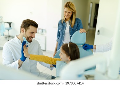 Male Doctor Is Giving Hi Five To Little Girl After A Successful Dental Examination.