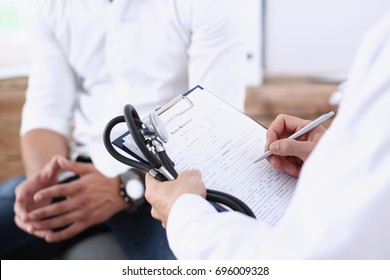 Male doctor hand hold silver pen filling patient history list at clipboard pad. Physical, exam, er, disease prevention, ward round, visit check, 911, prescribe remedy, healthy lifestyle concept