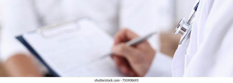 Male doctor hand hold silver pen and showing pad. Physical agreement form signature disease prevention ward round reception consent contract sign prescribe remedy healthy lifestyle concept