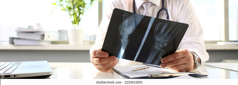Male doctor hold in arm silver pen and look at xray photography closeup. Skeleton bone disease exam medic aid or cancer physical test in hospital for healthy lifestyle education career concept - Shutterstock ID 1223413201