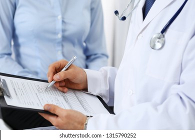 Male doctor holding application form while consulting female patient in hospital. Medicine and healthcare concept