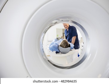 Male Doctor Looking At Patient Undergoing CT Scan