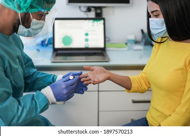 Male Doctor Making Blood Sugar Test To A Young Woman In Medical Clinic For Diabetes - Medical Worker And Patient Wearing Surgical Face Masks For Coronavirus Outbreak