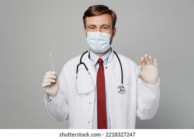 Male Doctor Man Wearing White Medical Gown Suit Mask Gloves Working In Hospital Do Coronavirus Covid-19 Rapid Test Isolated On Plain Grey Color Background Studio Portrait. Healthcare Medicine Concept