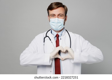 Male Doctor Man Wearing White Medical Gown Suit Sterile Disposable Protective Face Mask Gloves Show Heart Shape Gesture Work In Hospital Isolated On Plain Grey Background Healthcare Medicine Concept