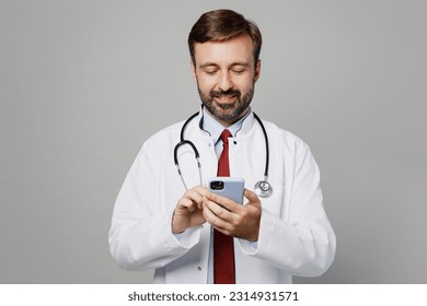 Male doctor man wears white medical gown suit stethoscope work in hospital use mobile cell phone consulting online isolated on plain grey color background studio portrait. Healthcare medicine concept - Shutterstock ID 2314931571
