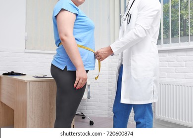 Male Doctor Measuring Waist Of Overweight Woman In Hospital