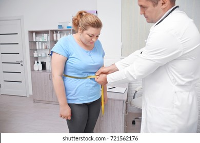 Male Doctor Measuring Waist Of Overweight Woman In Hospital