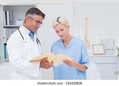 Male Doctor And Nurse Discussing Over Reports In Clinic