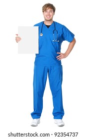 Male Doctor / Nurse Showing Billboard Sign. Young Medical Professional Wearing Blue Scrubs And Stethoscope Standing In Full Body Isolated On White Background.