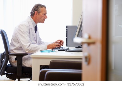 Male Doctor In Office Working At Computer