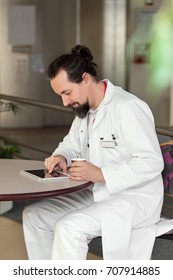 Male Doctor Is Reading Something In His Tablet In The Breakroom