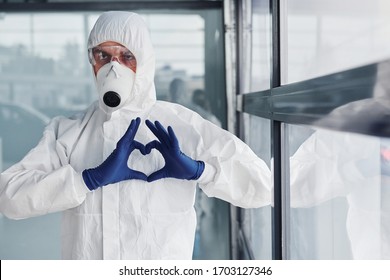 Male Doctor Scientist In Lab Coat, Defensive Eyewear And Mask Shows Love Gesture By Hands.