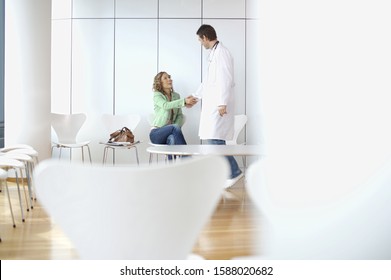 Male Doctor Shaking Hands With Woman In Waiting Room