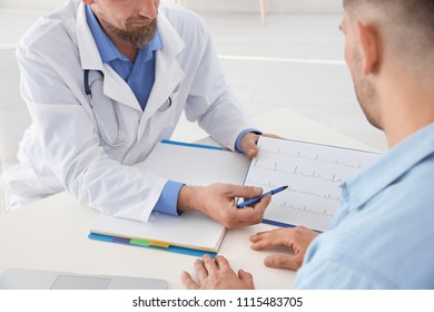 Male Doctor Showing Cardiogram To Patient In Clinic. Cardiology Consultation