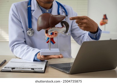 A male doctor sits at a table in a liver disease clinic, giving online advice on hepatitis A, D, E, pancreatitis, fatty liver, cirrhosis, liver cancer, and pancreatic cancer. - Powered by Shutterstock