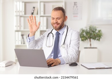 Male Doctor Sitting In An Office And Waving At A Laptop Computer