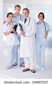 Male Doctor Standing In Front Of Team Using Digital Tablet