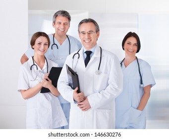 Male Doctor Standing In Front Of Team Using Digital Tablet