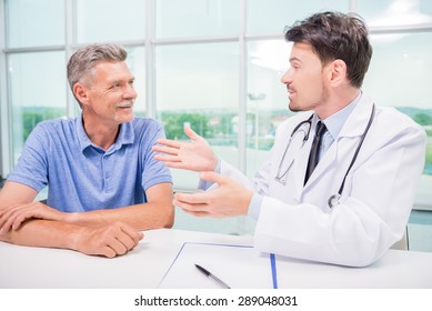 Male Doctor Talking With Patient Seriously At Clinic.