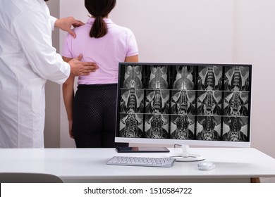 Male Doctor Therapist Treating Lower Back Pain Of Female Patient In Clinic