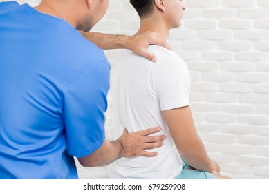 Male Doctor Therapist Treating Lower Back Pain Patient In Clinic Or Hospital - Physical Therapy Concept