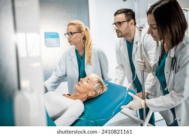 Male doctor and two female nurses in a hurry taking patient on hospital bed with intravenous drip to operation theatre. - Powered by Shutterstock