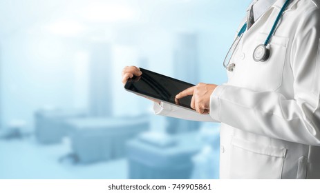 Male Doctor Using Tablet Computer To Analyze Patient Health Data Record, Standing On Hospital Background. Medical Technology Concept.