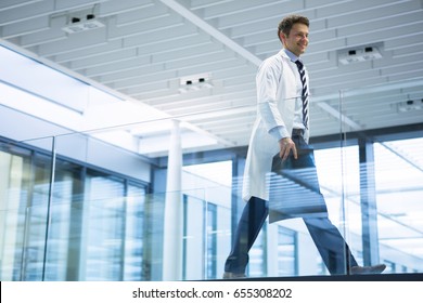 Male doctor walking with x-ray report in corridor at hospital - Powered by Shutterstock