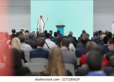 Male Doctor Waving At Audience From The Stage At A Medical Conference Event