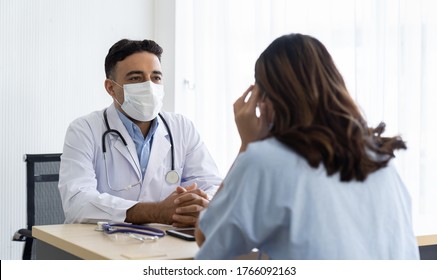 Male Doctor Wearing Face Mask Discussing With Woman Patient While Sitting On The Table In The Office At The Hospital