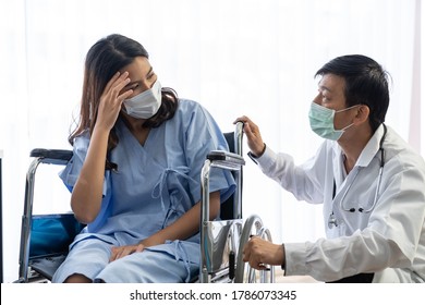 Male Doctor Wearing Face Mask In White Uniform Discussing With Woman Patient While Sitting On The Armchair In The Office At The Hospital.