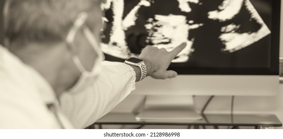 Male Doctor Wearing Mask In Covid-19 Department Looking At Ultrasound X-ray On The Computer Screen.