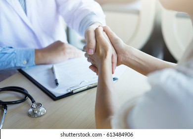 Male Doctor In White Coat Shaking Hand To Female Colleague. Patient Filling Thankful To Doctor.