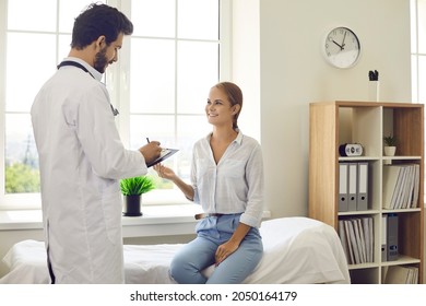 Male Doctor In White Medical Uniform Consult Female Patient In Private Hospital Or Clinic. Caring Man Therapist Or GP Write Prescription Do Checkup For Smiling Woman Client. Medicine Concept.