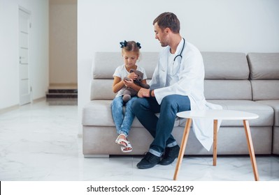 Male doctor in white uniform sits in the clinic with little girl. - Shutterstock ID 1520452199