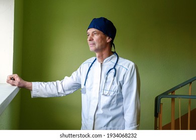 A male doctor in a white uniform stands on the stairs in the hospital.