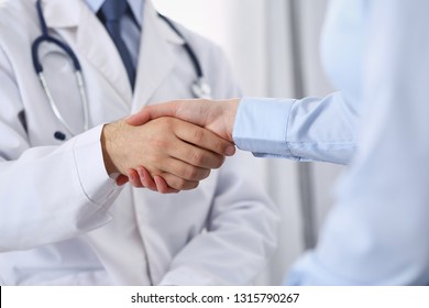 Male Doctor And Woman Patient Shaking Hands. Partnership In Medicine, Trust And Medical Ethics Concept