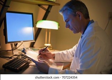 Male Doctor Working At Desk At Night