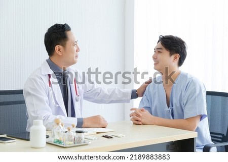 Male doctor and young male patient while consult and explain. Doctor and patient sitting together at table in clinic Foto stock © 