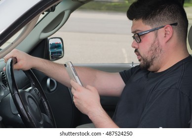 Male Driver Being Distracted By A Cell Phone Text Instead Of Watching The Road. Police In Rear View Mirror.